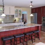 Large Two-tone kitchen.  White cabinetry on wall, cherry island, stone top